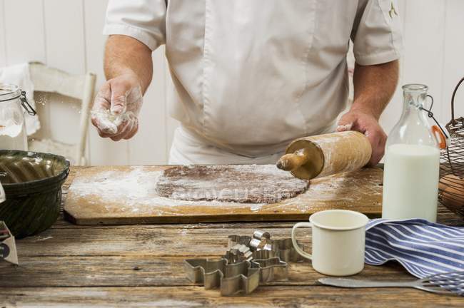 Обрезанный вид кондитера, посыпающего муку на тесто для печенья — стоковое фото