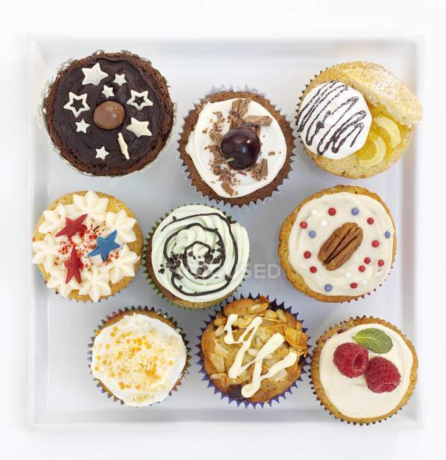 Assorted decorated cupcakes on square plate — Stock Photo