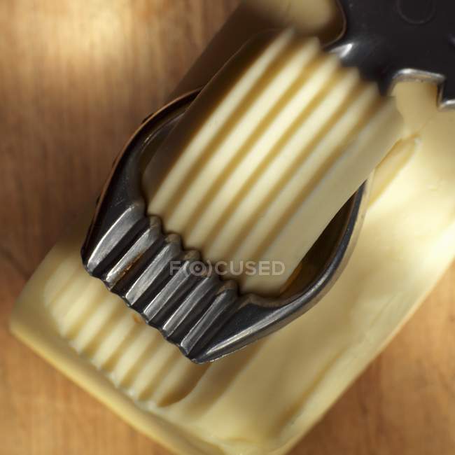 Closeup view of butter curler making curl from block of butter — Stock Photo