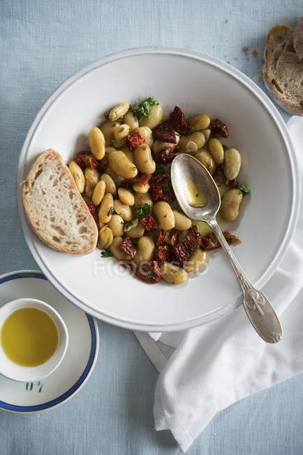 Top view of white bean salad with dried tomatoes and oil — Stock Photo