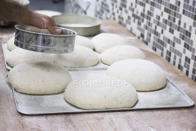 Hands sprinkling flour — Stock Photo