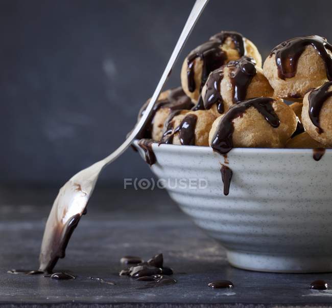 Bowl of profiteroles with chocolate sauce — Stock Photo