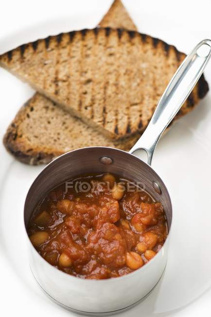 Closeup view of baked beans in pot with bread — Stock Photo