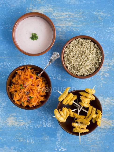 Top view of chicken Tandoori skewers with quinoa, carrot salad and Raita in  bowls — Stock Photo