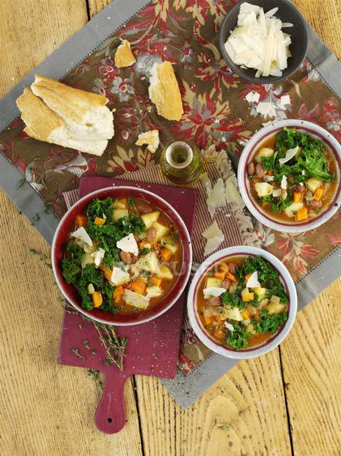 Vegetable soup with borlotti beans and green kale over wooden surface — Stock Photo
