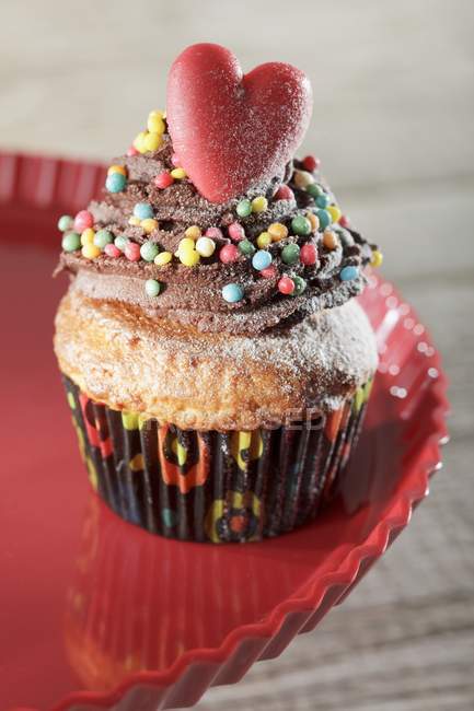 Cupcake decorated with colored sprinkles and heart — Stock Photo