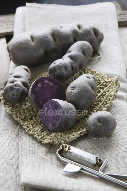 Ganze und halbierte violette Trüffelkartoffeln — Stockfoto