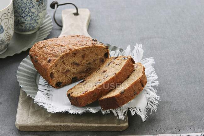 Closeup view of sliced fruit loaf on cloth, plate and wooden board — Stock Photo