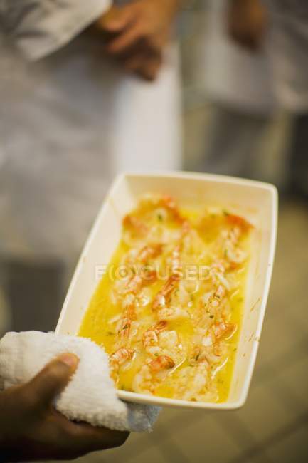 Hand holding dish of Prawns in butter — Stock Photo