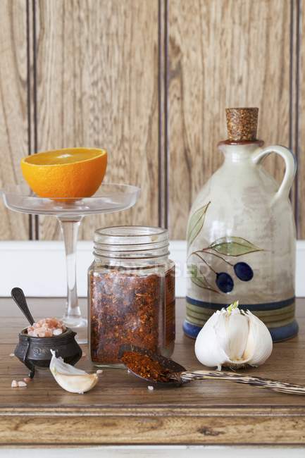 Una disposizione di olio d'oliva, aglio, peperoncino e sale su superficie e fondo in legno — Foto stock