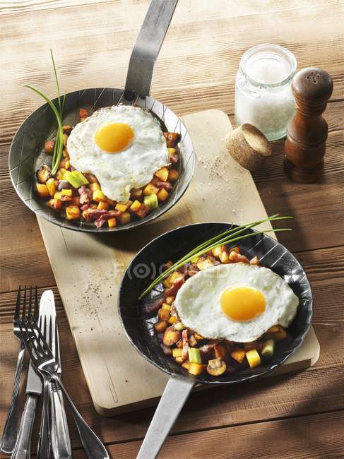 Fried potatoes and egg in frying pans — Stock Photo