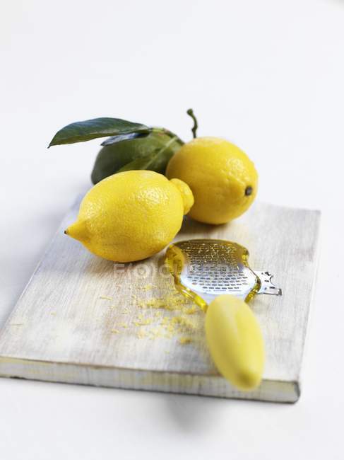 Limones con rallador y ralladura de limón - foto de stock