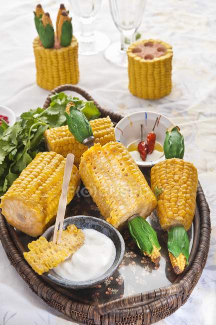 Vista de cerca de mazorcas de maíz dulce con crema agria y aceite - foto de stock