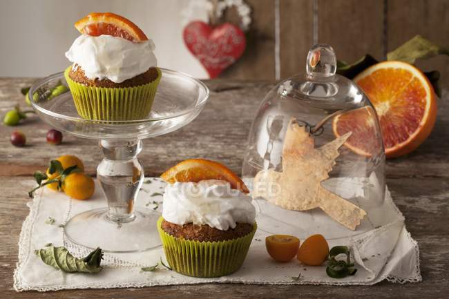 Cupcakes laranja na toalha de mesa e rack de bolo — Fotografia de Stock