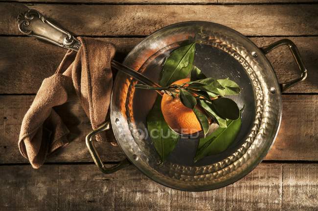 Orange in copper saucepan — Stock Photo