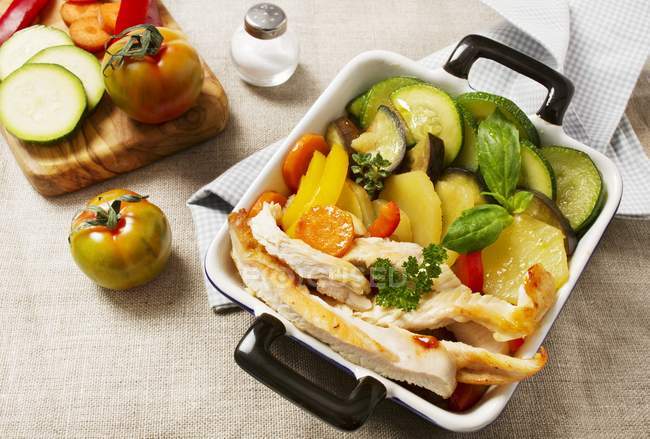 Ratatouille with chicken in baking dish over towel — Stock Photo