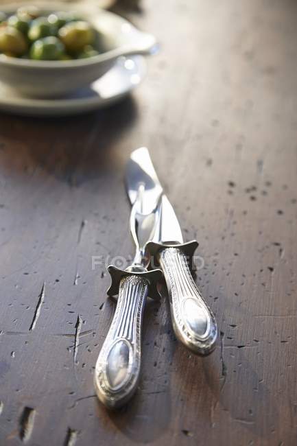 Vista de cerca de un cuchillo de talla y tenedor en una mesa de madera - foto de stock