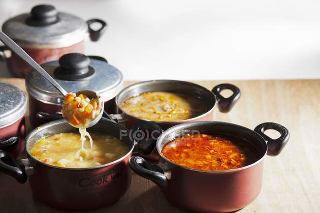 Различные овощные супы в горшках на деревянной поверхности — стоковое фото