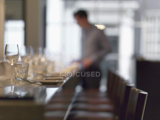 Row of chairs at restaurant table and blurred person on background — Stock Photo