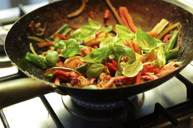Stir-fried prawns with vegetables and basil in wok — Stock Photo