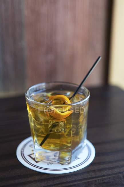 Крупный план напитка со льдом и апельсиновой цедрой — стоковое фото