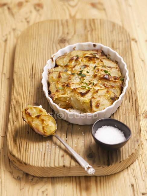 Potato gratin on spoon and in dish — Stock Photo