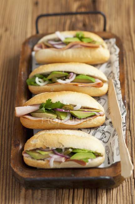 Ham, avocado and red onion rolls over wooden desk — Stock Photo