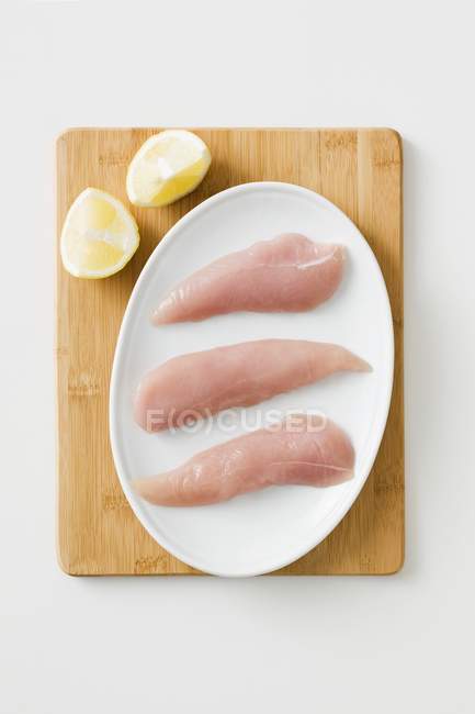 Raw Chicken fillets and halved lemon — Stock Photo