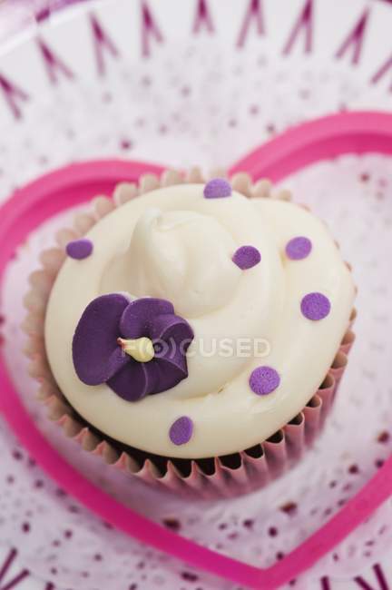 Cupcake decorated with purple sugar flower — Stock Photo
