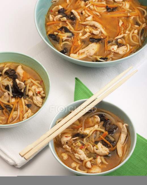 Vista de cerca de sopa de pollo chino en tres tazones - foto de stock