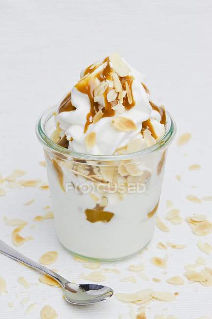 Vue rapprochée du yaourt glacé aux amandes effilées et à la sauce caramel — Photo de stock