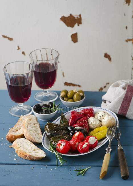An appetiser platter with stuffed vine leaves and vegetables, white bread and red wine — Stock Photo