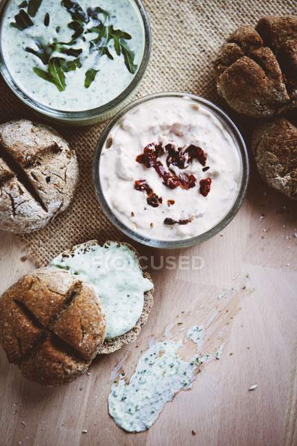 Bread rolls with various spreads on wooden surface — Stock Photo