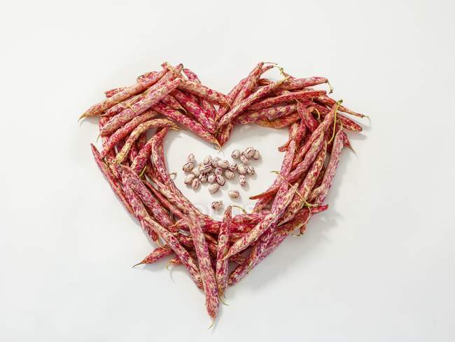 Un cœur fait de haricots borlotti sur une surface blanche — Photo de stock