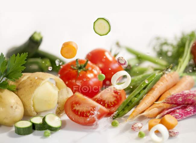 Ingredientes para a sopa vegetal que põe na superfície branca — Fotografia de Stock