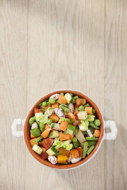 Un tazón de verduras de sopa sobre la superficie de madera - foto de stock