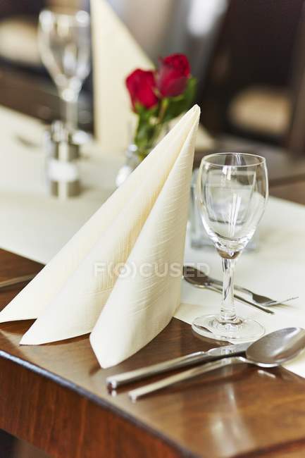 Elevated view of a place setting with a napkin, a glass and cutlery in a restaurant — Stock Photo