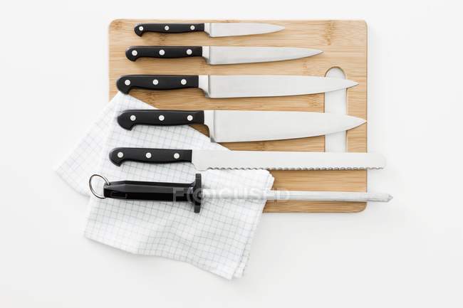 Vari coltelli e un acciaio affilante su un tagliere — Foto stock