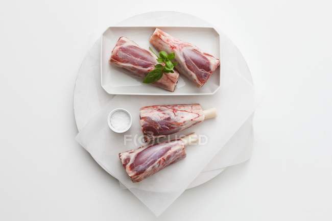 Raw Knuckles of lamb with salt and basil — Stock Photo