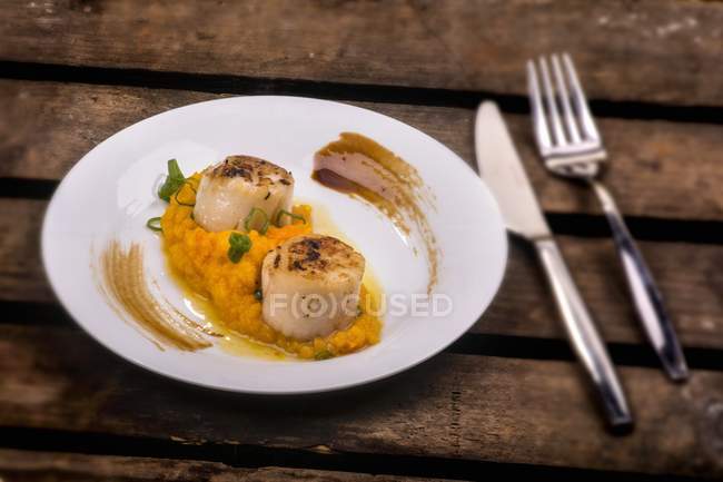 Scallops on a bed of mashed pumpkin and truffles  on white plate  over wooden surface — Stock Photo