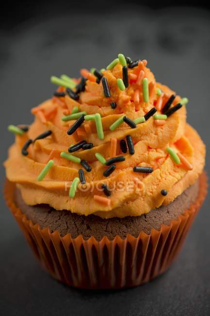 Cupcake com creme de manteiga de laranja e polvilhas de açúcar — Fotografia de Stock