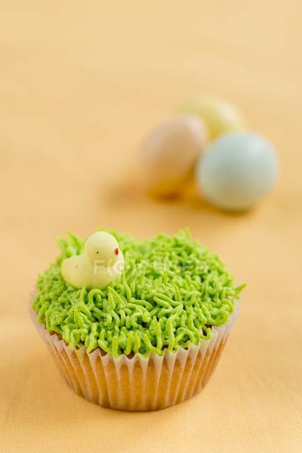 Cupcake decorated with grass and chick — Stock Photo