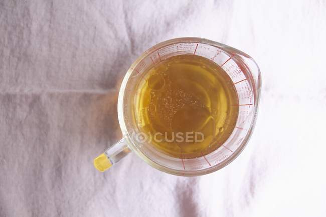 Vista superior de óleo em um jarro de medição em uma superfície branca — Fotografia de Stock