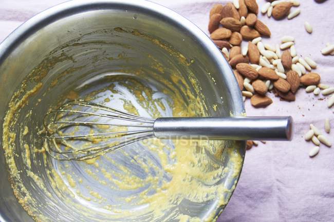 Closeup top view of cream remains in bowl with almonds and pine nuts nearby — Stock Photo