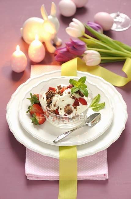 Nahaufnahme von Keksen und Sahne mit Erdbeeren dekoriert mit brennenden Kerzen und Blumen — Stockfoto