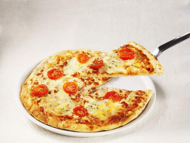 Pizza Margarita con rebanada en espátula - foto de stock