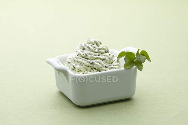 A bowl of herbal butter on a light green surface — Stock Photo