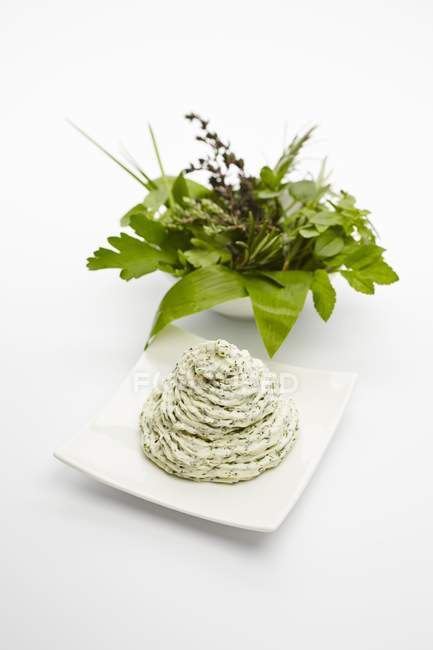 Beurre à base de plantes près d'un bol d'herbes fraîches — Photo de stock