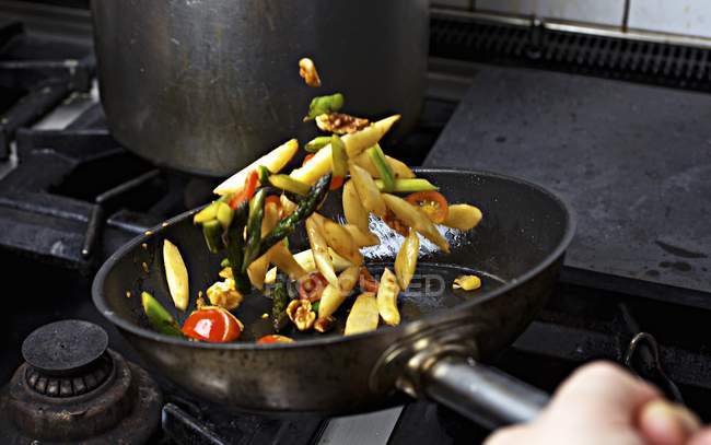 Vegetables being sauteed in a pan on a hob — Stock Photo