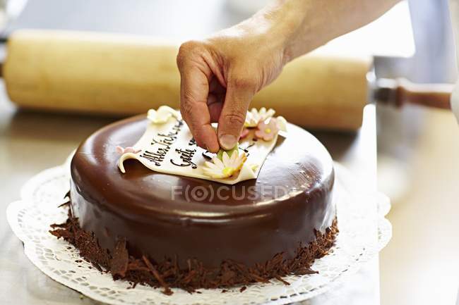 Обрізаний вид людини, що прикрашає шоколадний торт з марципаном — стокове фото